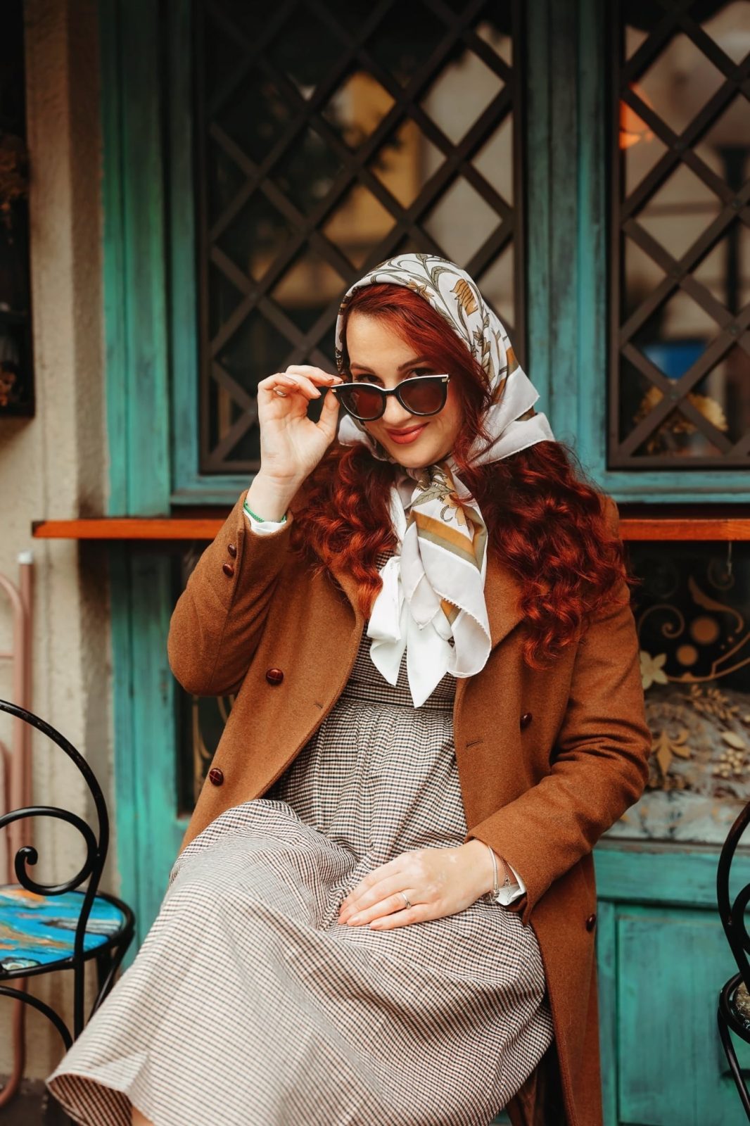 Mlada crvenokosa žena sjedi pored vintage prozora