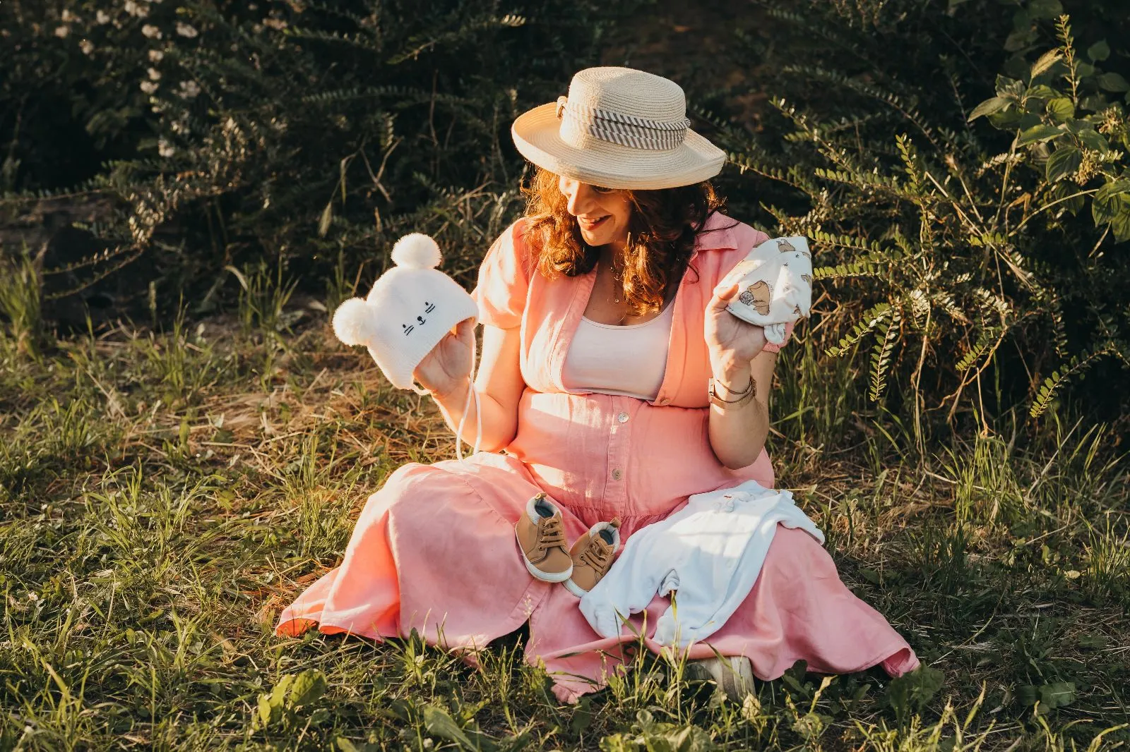 Trudnica sjedi na travi u zlatnom satu, okružena prirodom