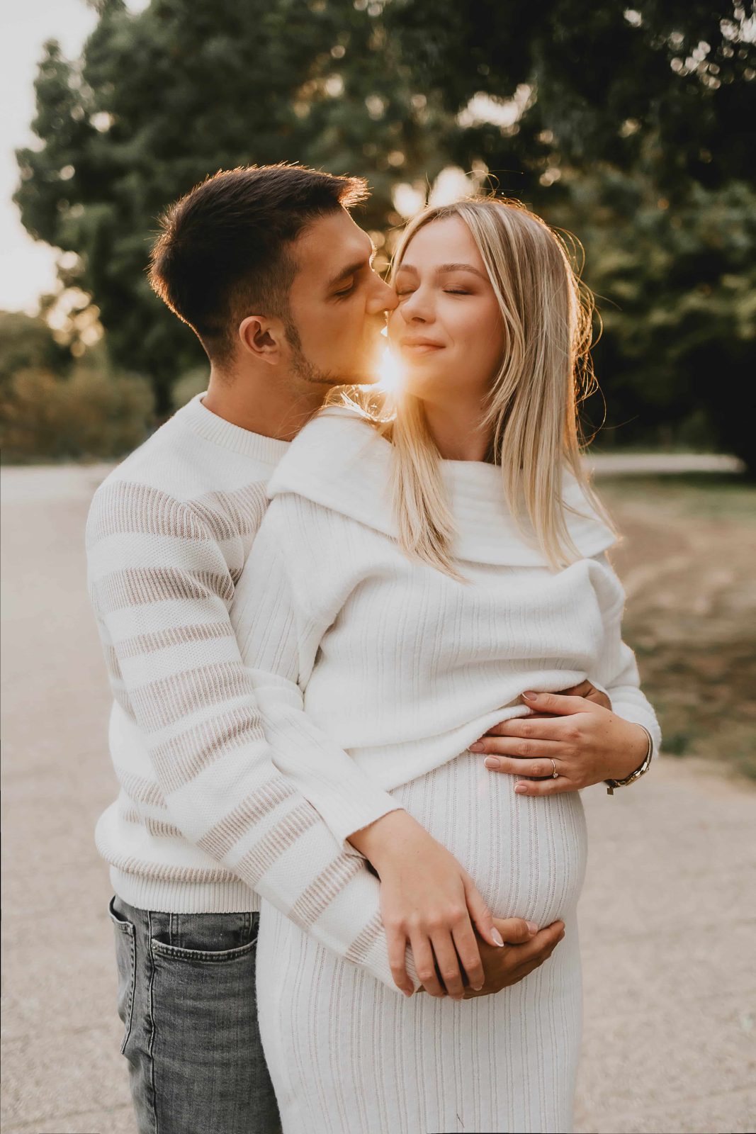 Trudnica u dugoj haljini obasjana suncem pri zalasku